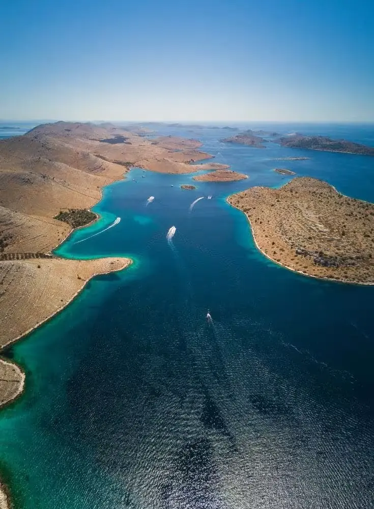 Aerial view of the Kornati islands with boats in turquoise channels.