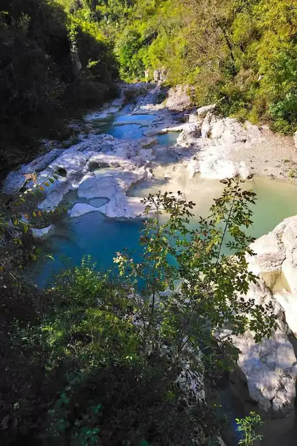 Turquoise limestone cauldrons at Kotli with a thin waterfall ribbon.