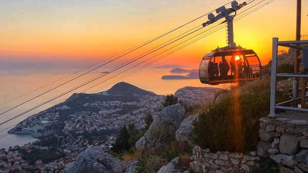 Dubrovnik cable car cabin gliding above Old Town and Lokrum Island.