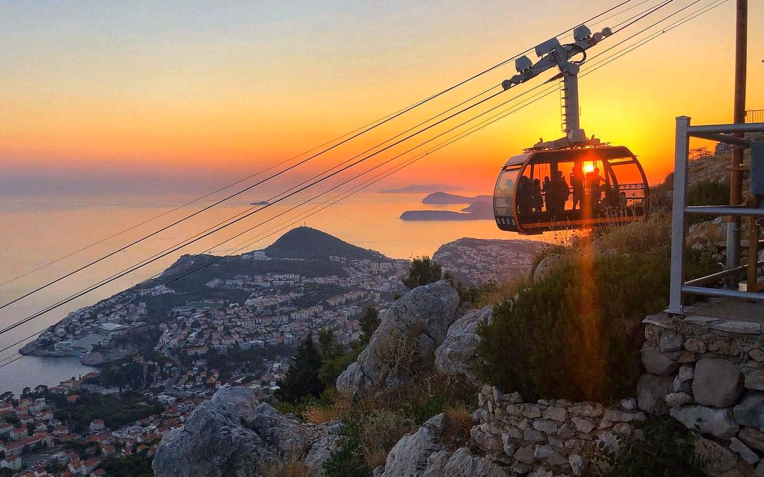 Dubrovnik cable car cabin gliding above Old Town and Lokrum Island.