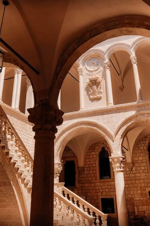 Small courtyard of Rector's Palace with staircase, arches and clock.