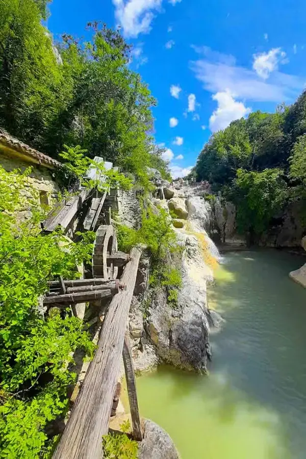 Kotli waterfall pouring into natural limestone cauldrons beside an old mill.
