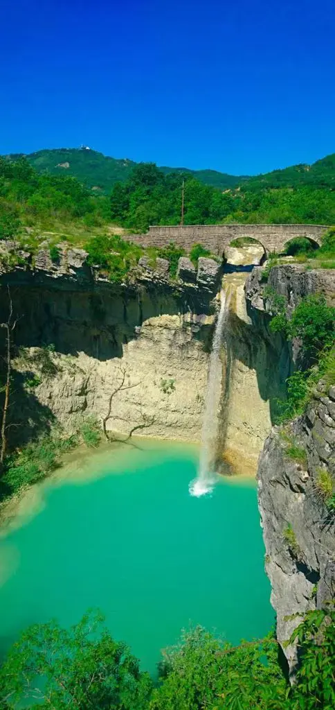 Narrow plume of Sopot plunging into a turquoise plunge pool.