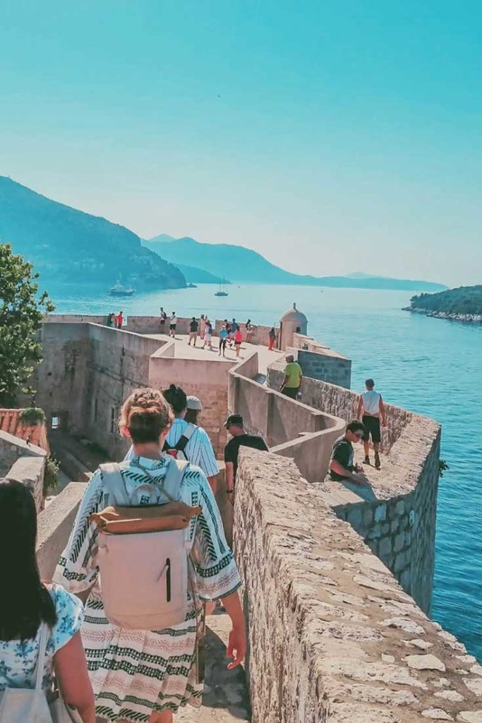 Narrow seaside passage along Dubrovnik City Walls near water edge.